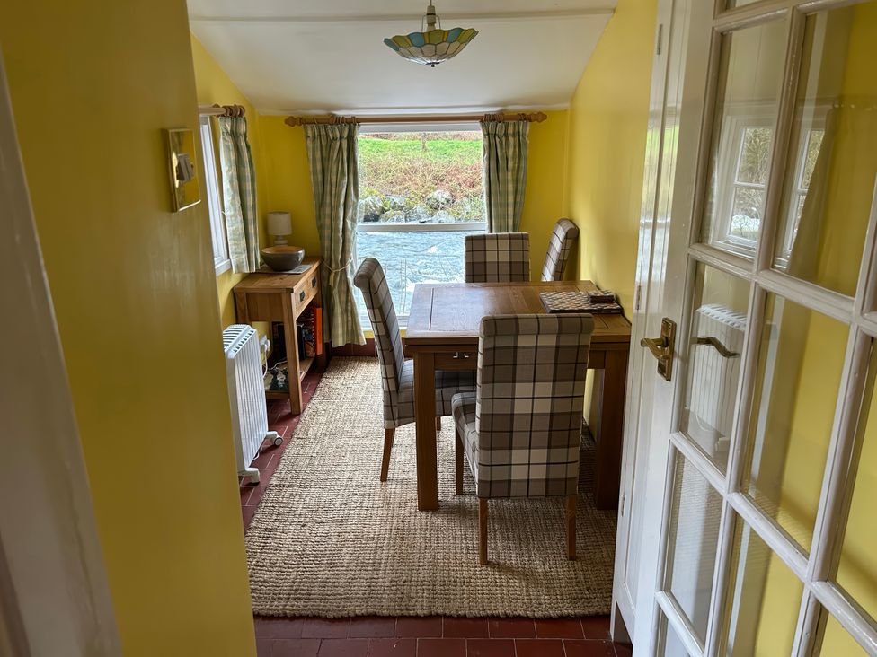 A dining room with a table and chairs at Riverbank Cottage in Beddgelert