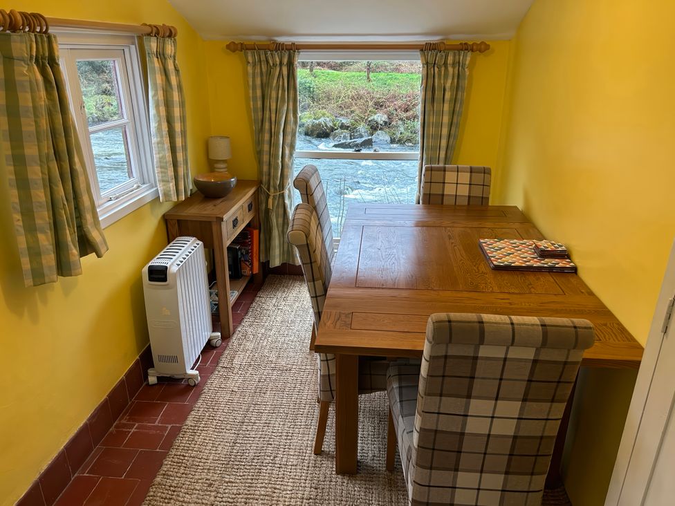 A dining room with a table and chairs at Riverbank Cottage Beddgelert