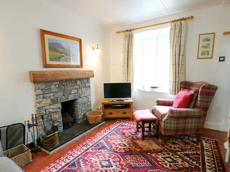 A living room with a fireplace and television at Riverbank Cottage in Beddgelert