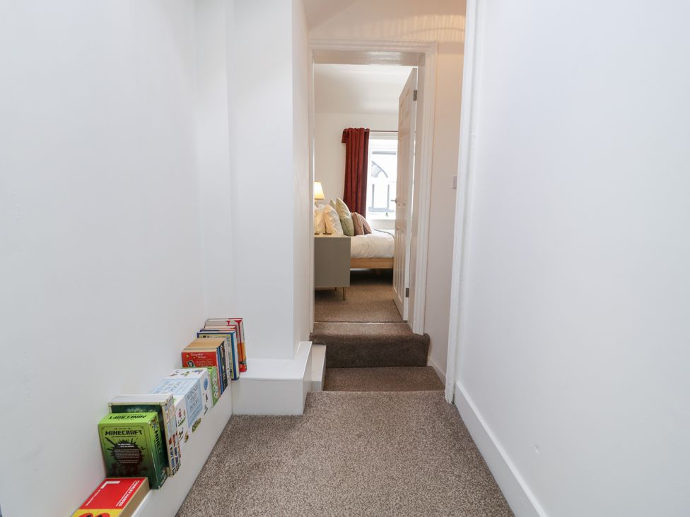 A hallway with books on a shelf and a view of a bedroom at Derwen House Llangollen