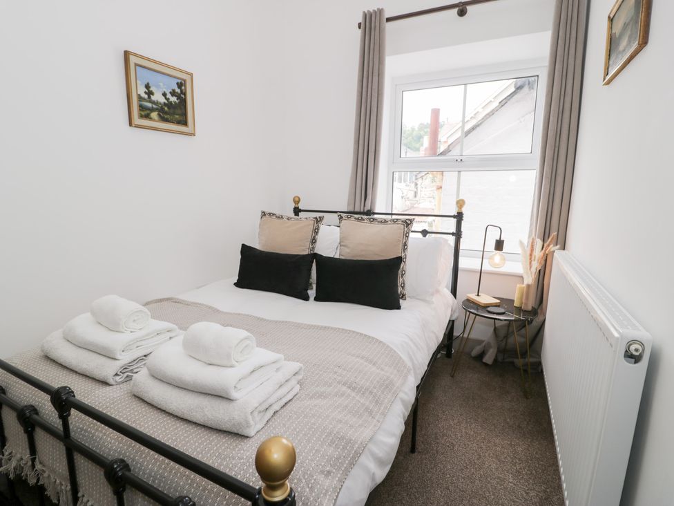 A bedroom with a bed and side table at Derwen House in Llangollen