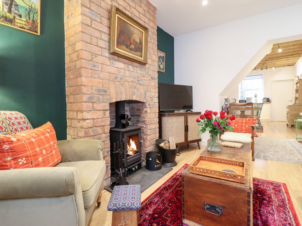 A living room with a wood stove and a coffee table at Derwen House in Llangollen