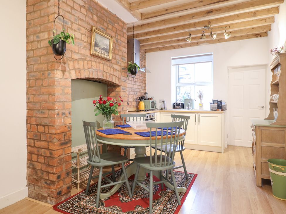 A kitchen with dining table and brick wall at Derwen House Llangollen