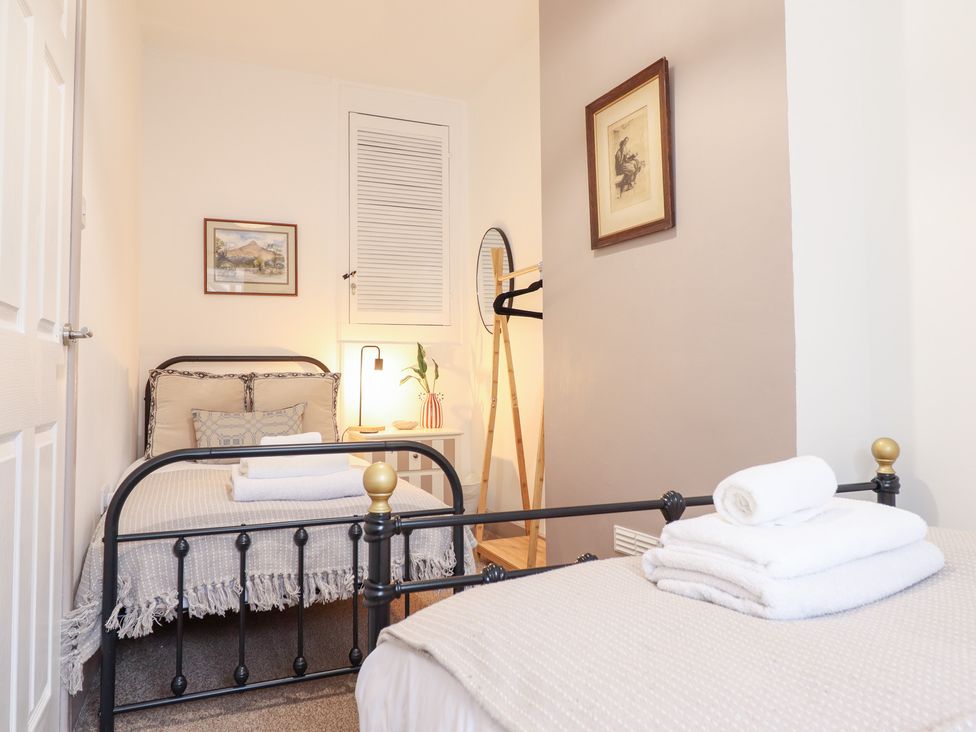 A bedroom with two beds and a lamp at Derwen House in Llangollen