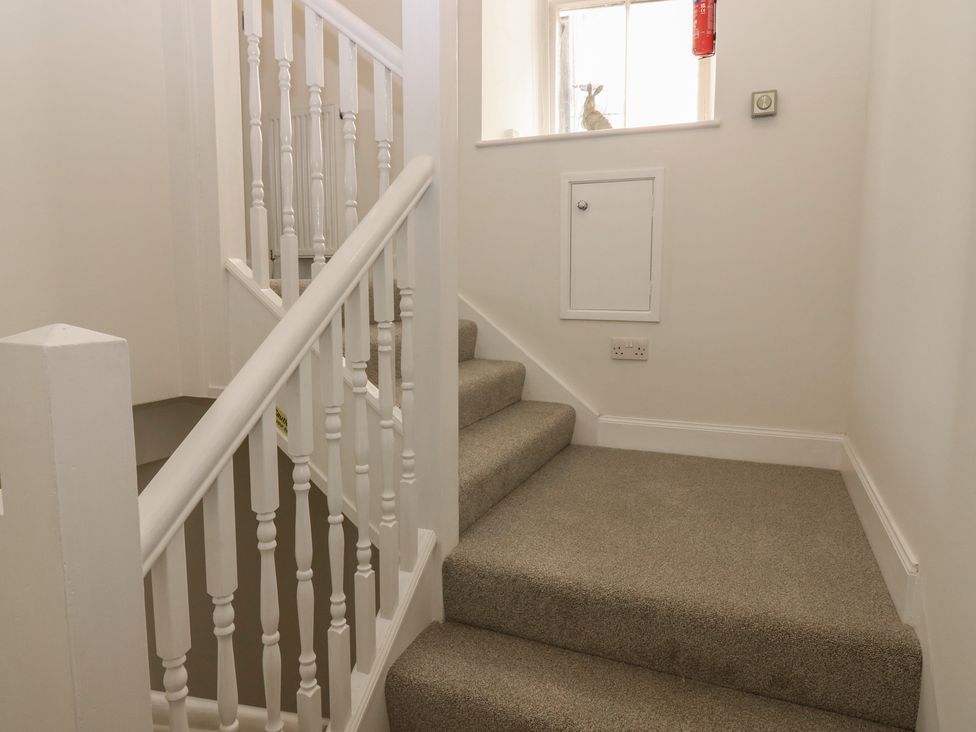 A staircase with a handrail and light switch at 21A High Street Jedburgh