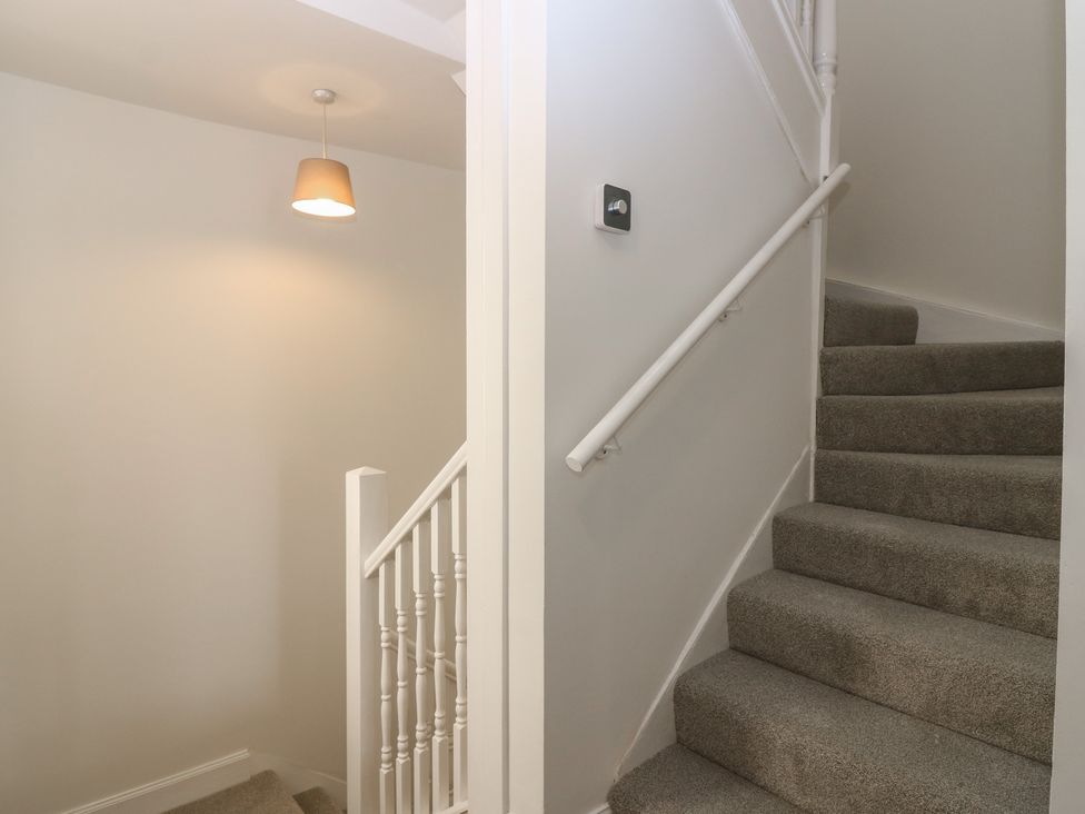 A staircase with carpet and a light fixture at 21A High Street in Jedburgh