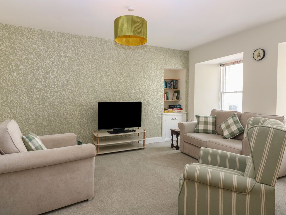 A living room with a television and bookshelf at 21A High Street, Jedburgh