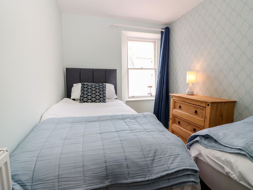 A bedroom with two beds and wooden furniture at 21A High Street in Jedburgh