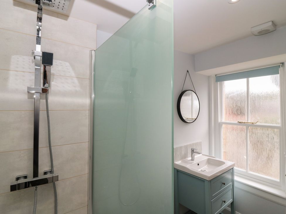 A bathroom with a shower, sink, and window at 21A High Street in Jedburgh