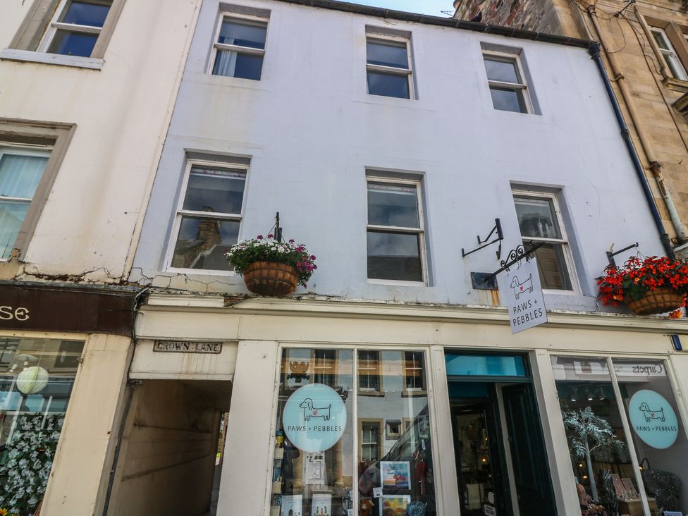 A store front with a sign and flowers next to windows at 21A High Street in Jedburgh
