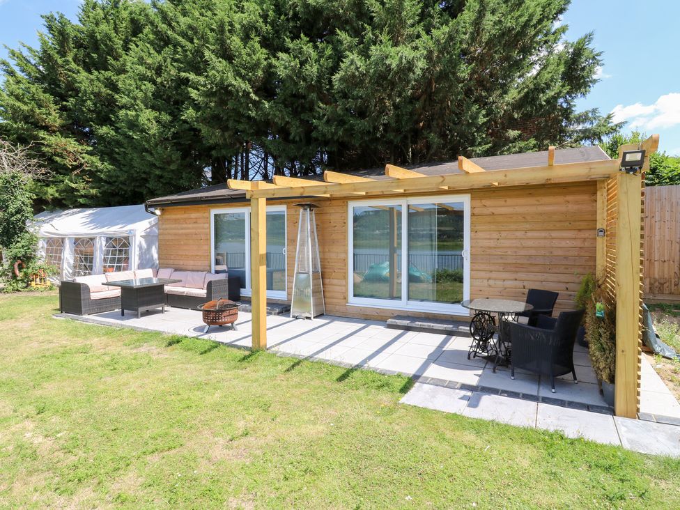 A wooden building with outdoor seating and a terrace at Haymens Wharf Wouldham