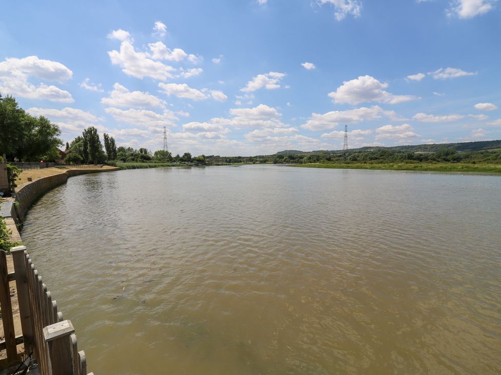 A river with trees and power lines in the background at Haymens Wharf Wouldham