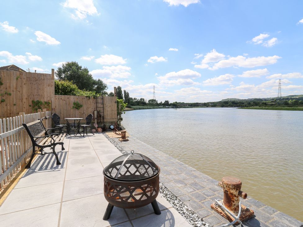 An outdoor area with a river view and seating at Haymens Wharf Wouldham