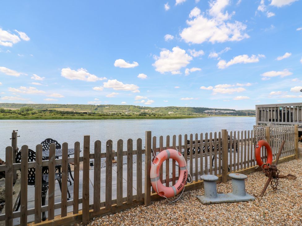 An outdoor area by a river with a fence and chairs at Haymens Wharf Wouldham