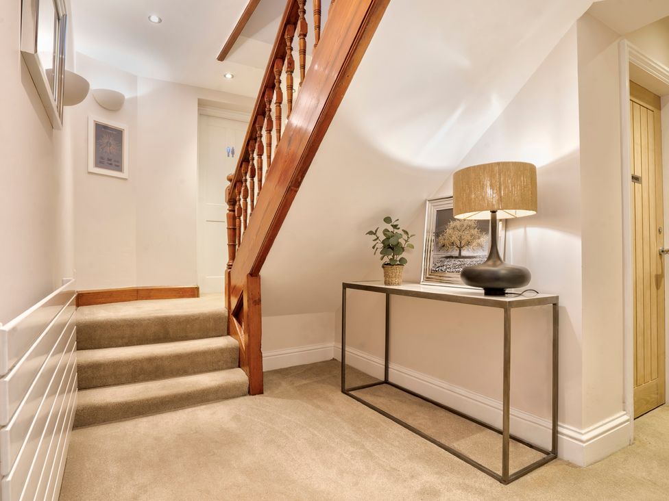A staircase with a console table and lamp in a hallway at Rosemount Boutique Windermere