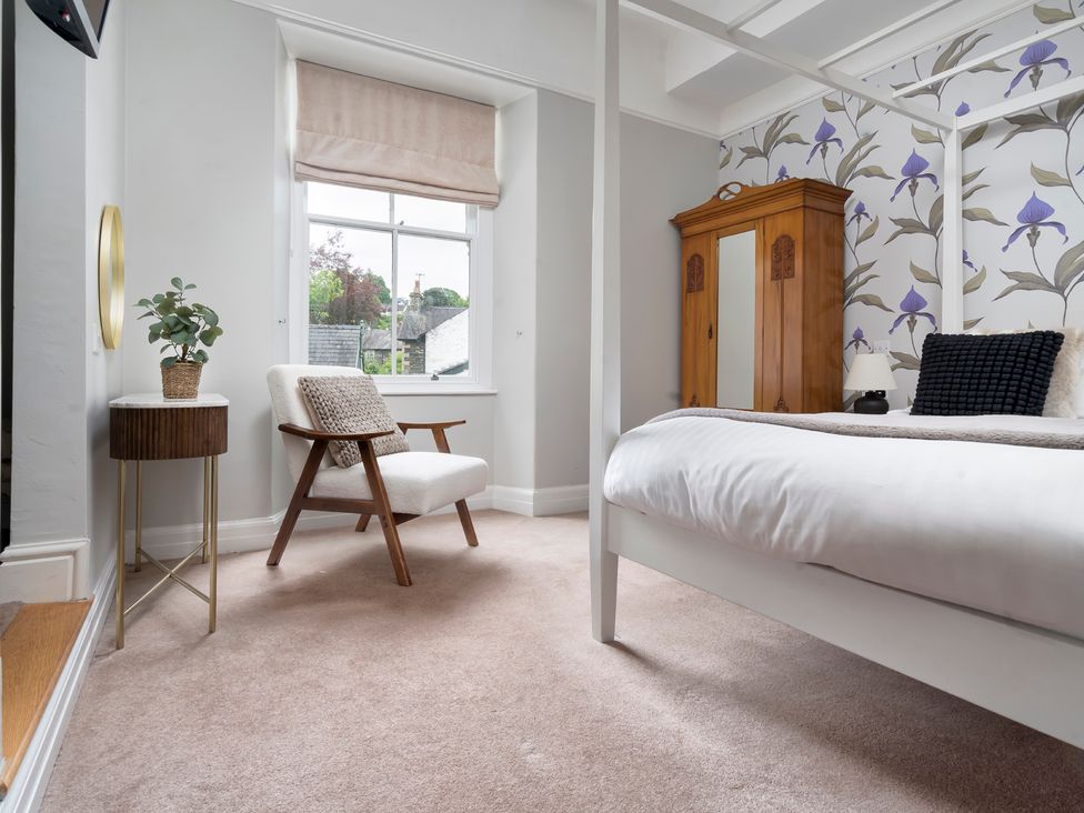 A bedroom with a bed and an armchair at Rosemount Boutique in Windermere