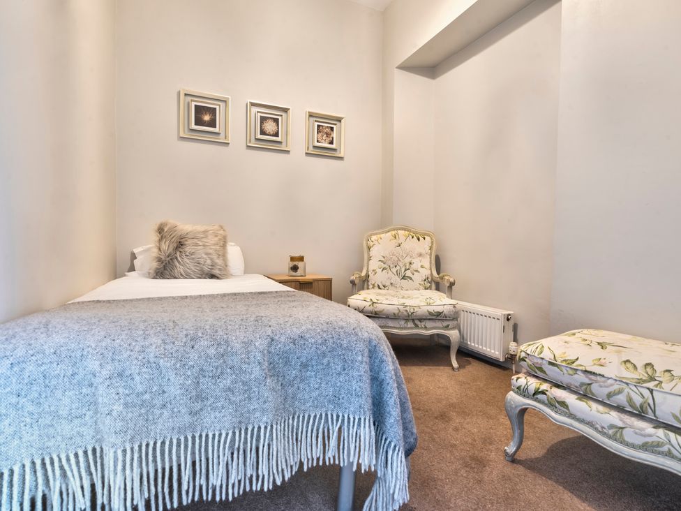 A bedroom with a bed, chairs, and framed pictures at Rosemount Boutique in Windermere