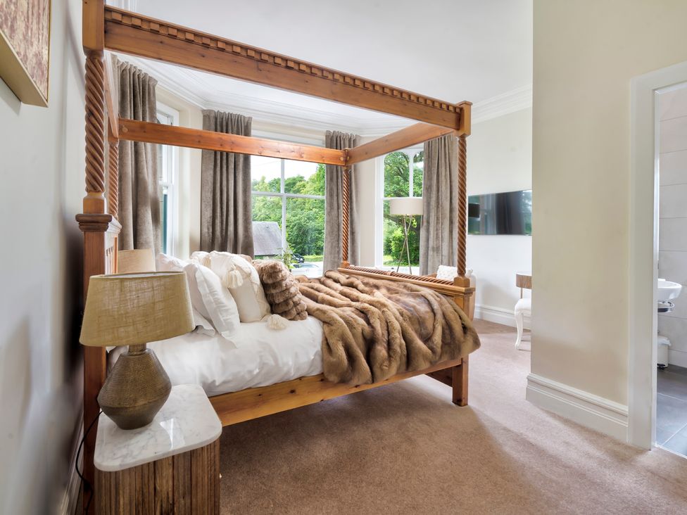 A bedroom with a wooden bed and a television in Rosemount Boutique Windermere