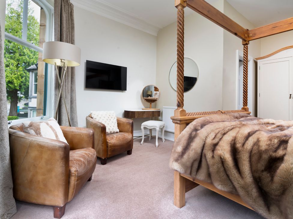A bedroom with a four-poster bed and two chairs at Rosemount Boutique in Windermere
