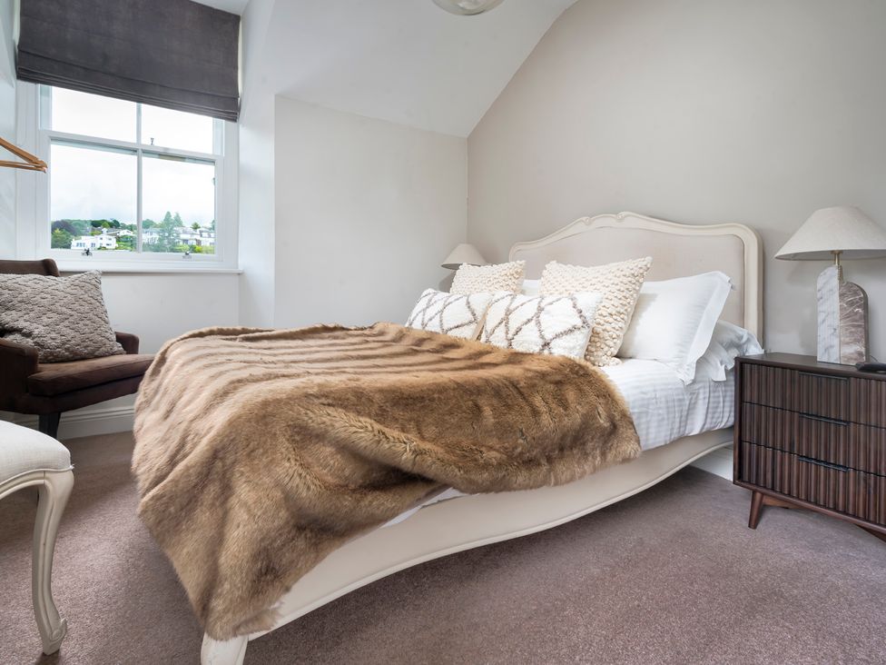 A bedroom with a bed and chair at Rosemount Boutique in Windermere