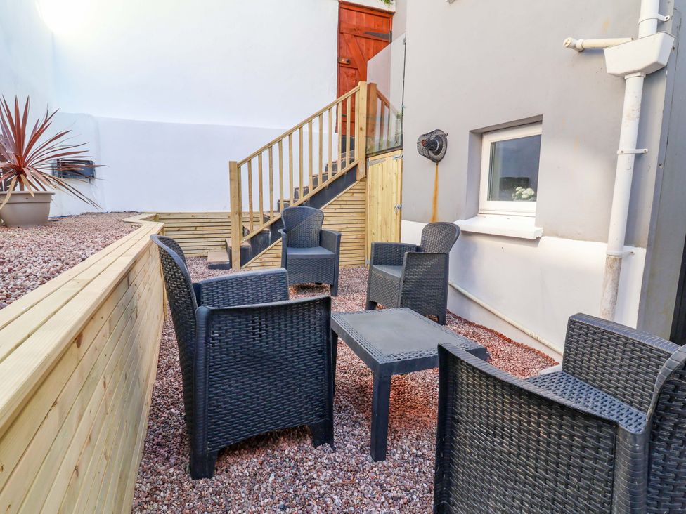 An outdoor seating area with chairs and a table at Hollycombe in Ilfracombe