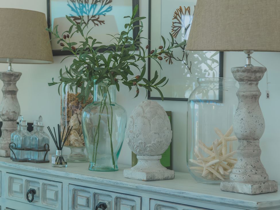 A sideboard with lamps glass jars and decorative items at Oystercatcher Mevagissey