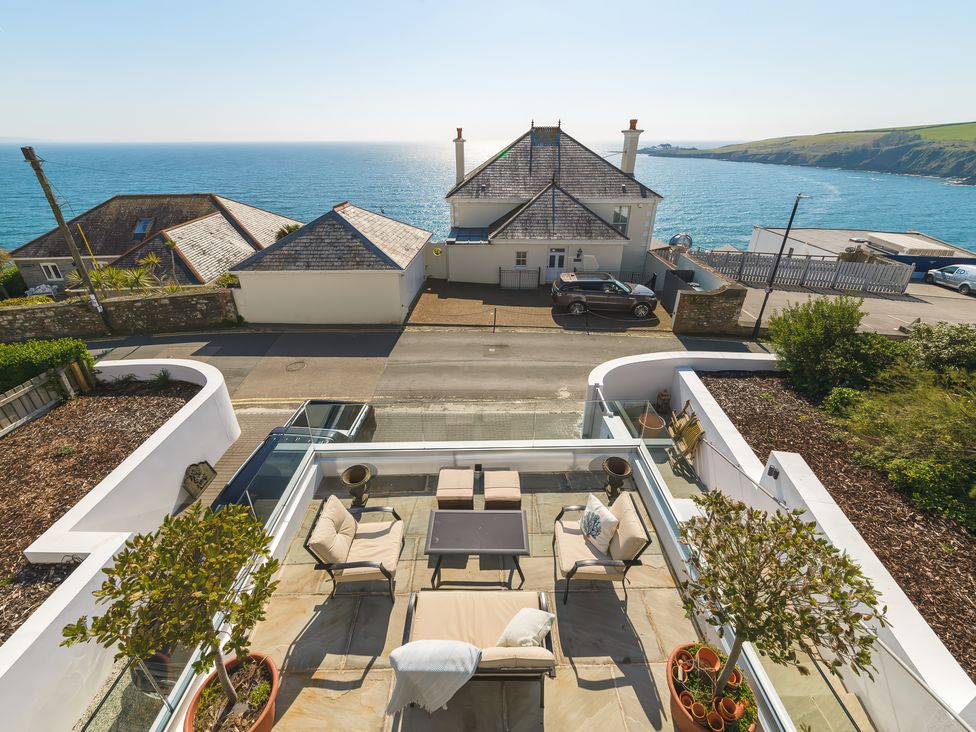 A patio with outdoor seating and potted plants overlooking the sea at Oystercatcher in Mevagissey