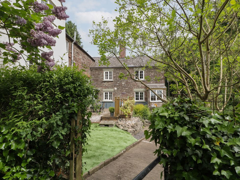 A garden with a house and pathway at Court House Cottage Gatcombe near Blakeney