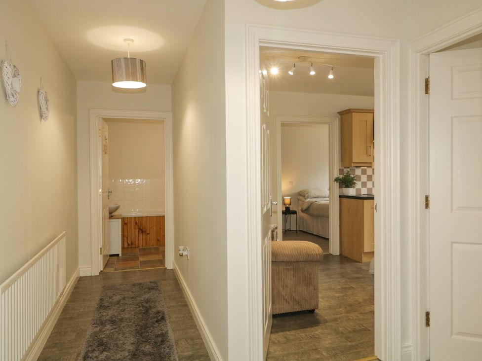 A hallway with multiple doors leading to a kitchen and bedroom at Woodside Guest House in Castlerock