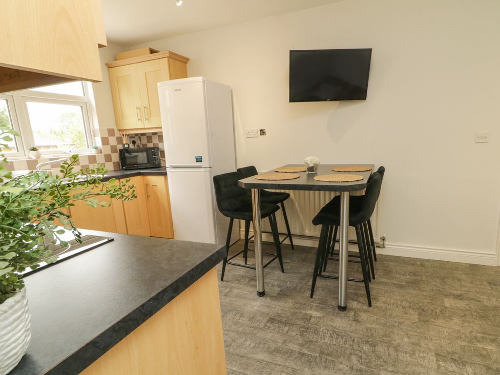 A kitchen with a table and stools at Woodside Guest House Castlerock
