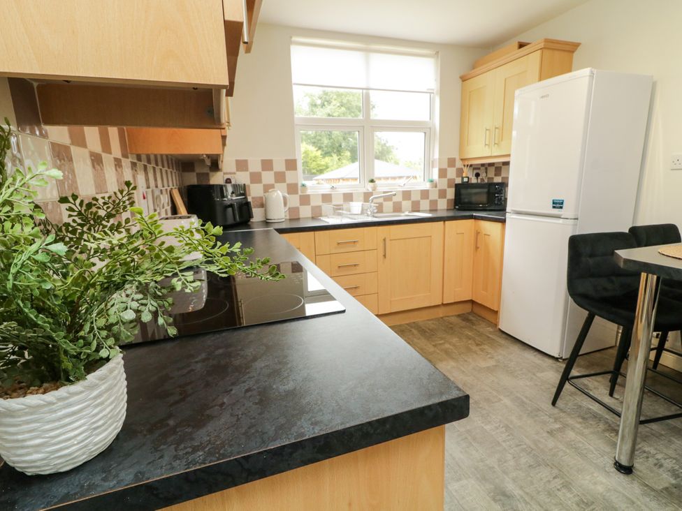 A kitchen with appliances and a dining table at Woodside Guest House in Castlerock
