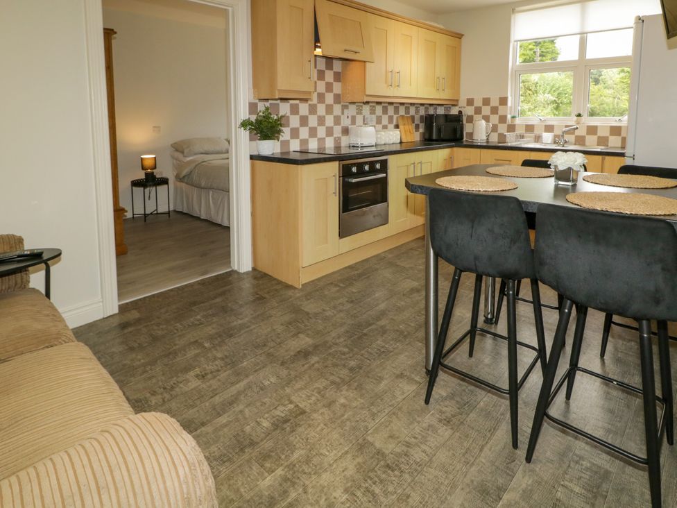 A kitchen with bar stools and a dining table at Woodside Guest House in Castlerock