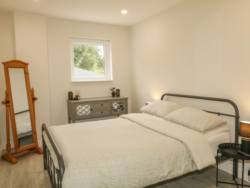 A bedroom with a bed and a mirror at Woodside Guest House in Castlerock