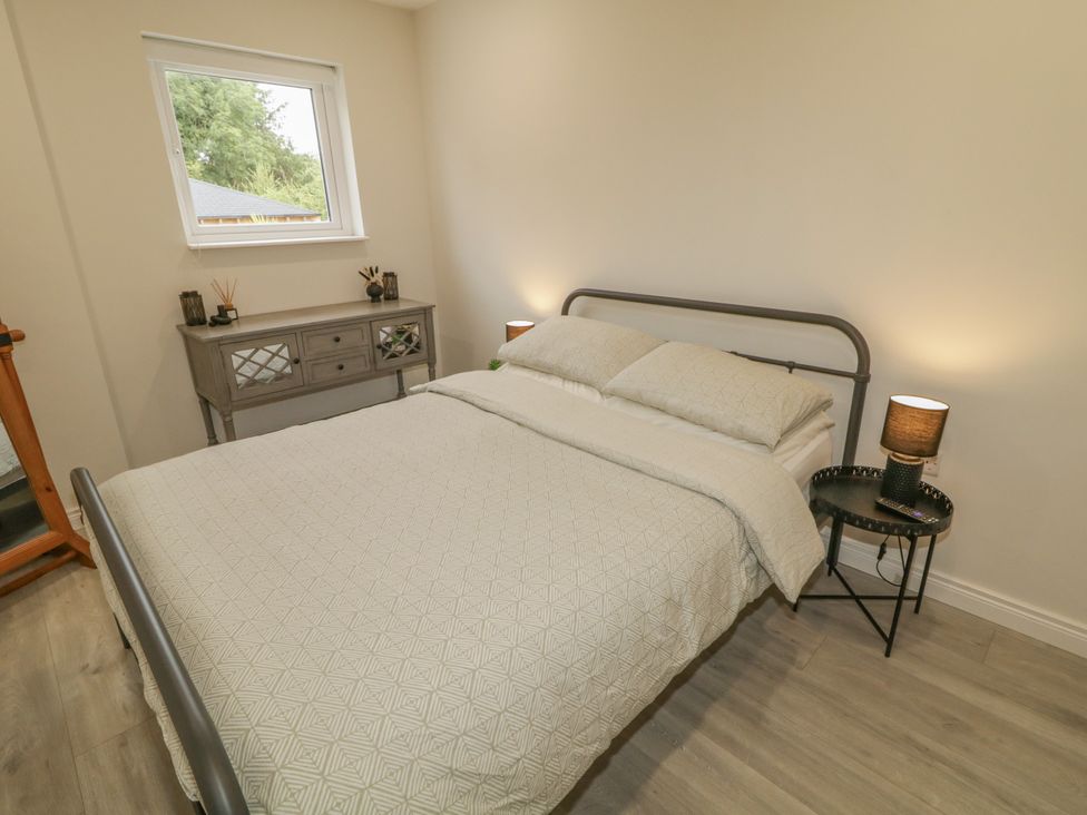 A bedroom with a bed and nightstand at Woodside Guest House Castlerock