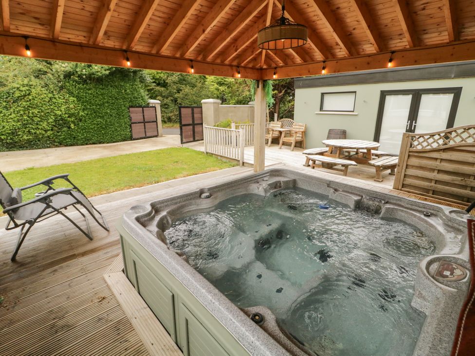 An outdoor area with a hot tub and seating at Woodside Guest House in Castlerock