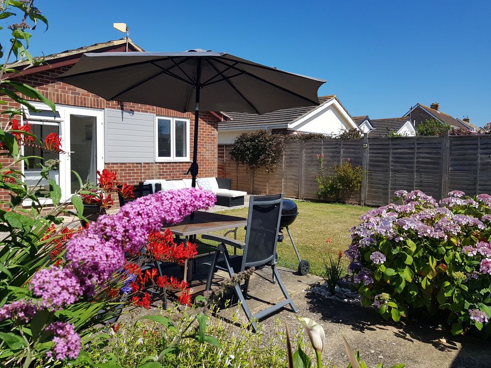 A garden with a table and chairs under an umbrella at Seafarer's Rest in Selsey