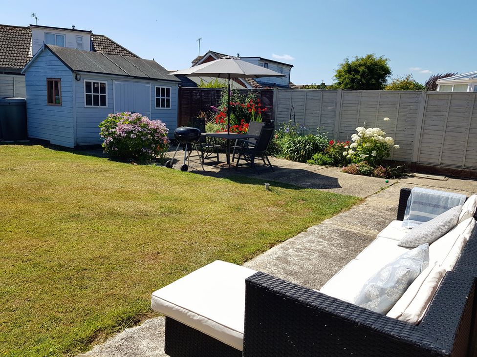 A garden with a shed, table, chairs, and flowers at Seafarer's Rest Selsey