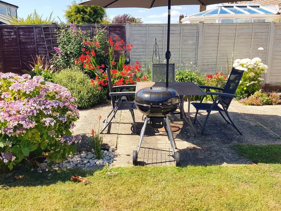 A garden with a table and chairs under an umbrella at Seafarer's Rest in Selsey