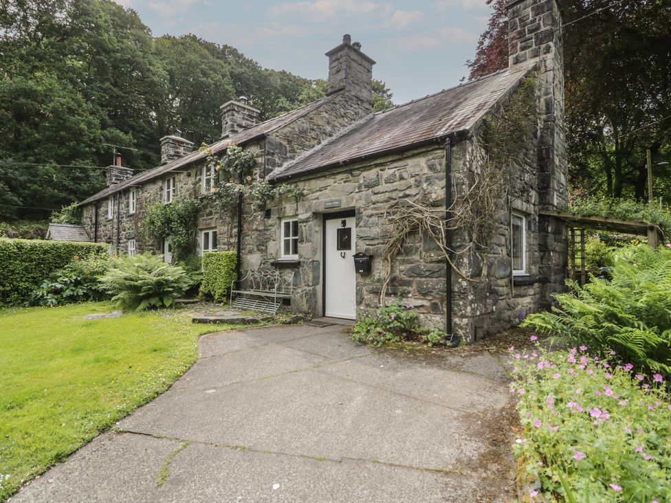 A stone house with a garden and pathway at Glandwr Cottage in Llanbedr