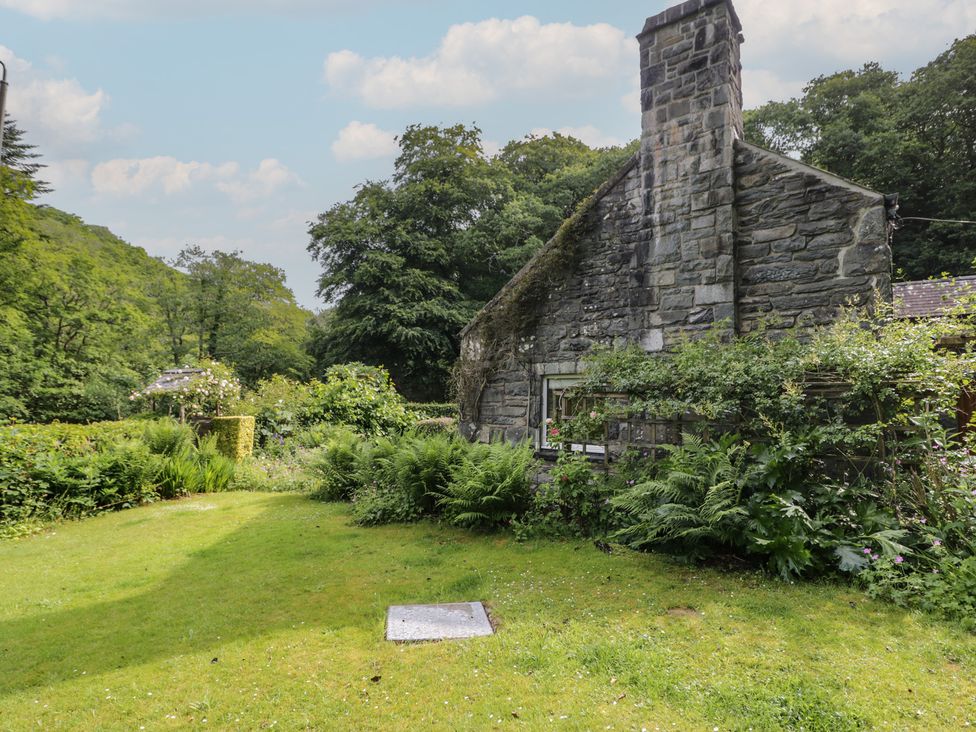 A garden area with stonework and plants at Glandwr Cottage Llanbedr