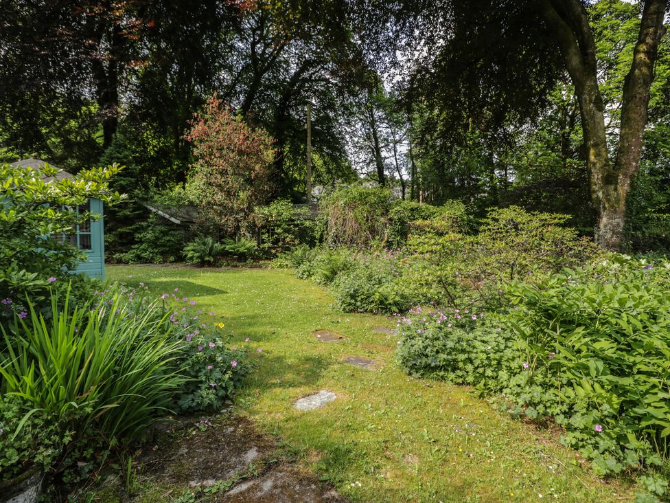 A garden with flowers and trees at Glandwr Cottage in Llanbedr