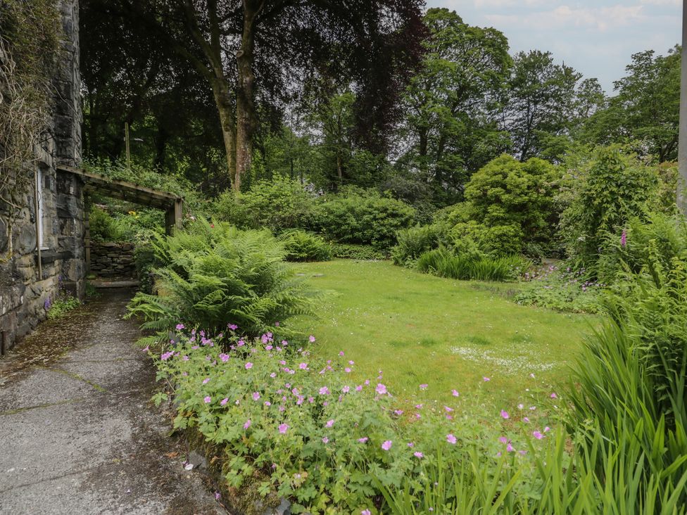 A garden with pathway and flowers at Glandwr Cottage in Llanbedr