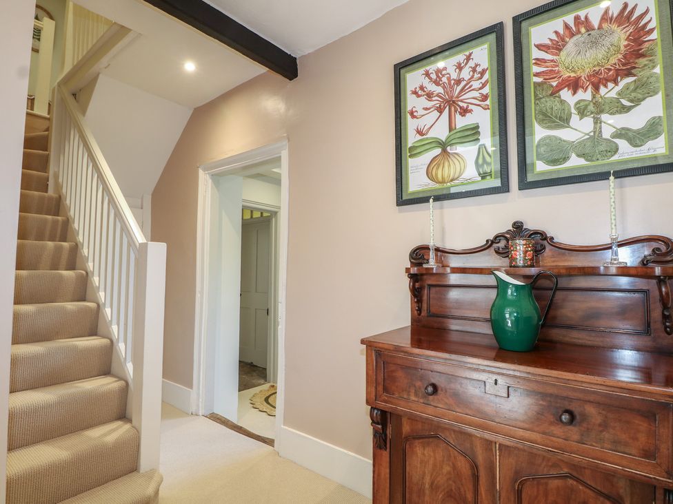 A hallway with a staircase and cabinet at Rectory Cottage Chawton near Alton Hampshire