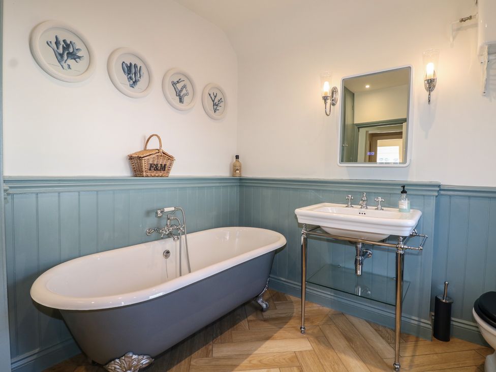 A bathroom with a bathtub and washbasin at Rectory Cottage in Chawton near Alton, Hampshire