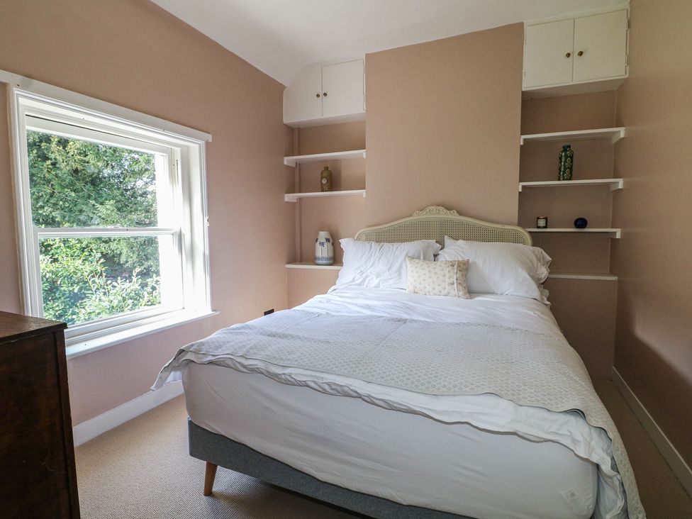 A bedroom with a bed and shelves at Rectory Cottage in Chawton near Alton, Hampshire