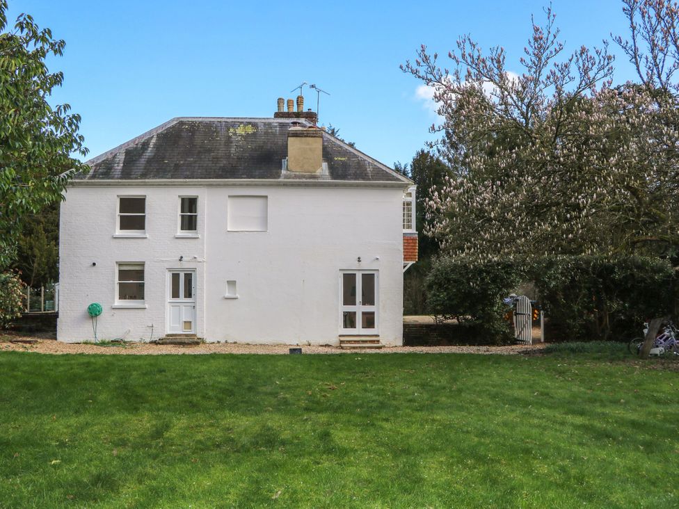 A house with a green lawn and trees at Rectory Cottage in Chawton near Alton, Hampshire
