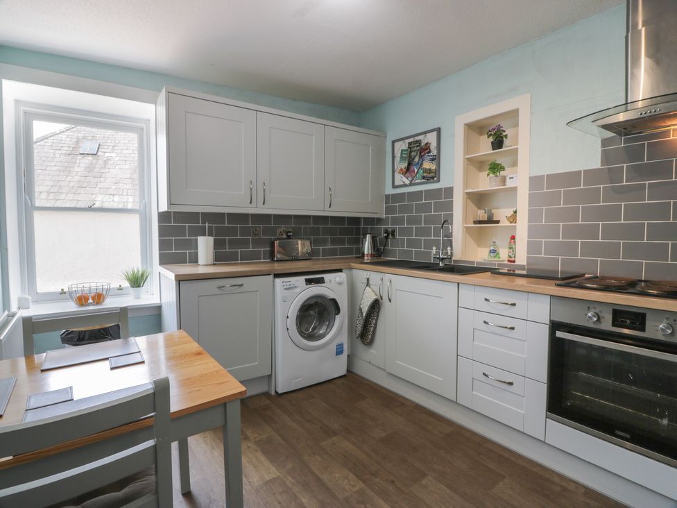 A kitchen with a washing machine and table at Fleet Townhouse in Castle Douglas