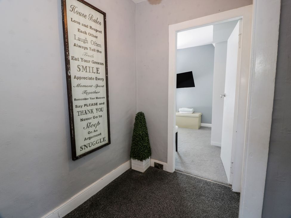 A hallway with a framed sign and a decorative plant at Fleet Townhouse in Castle Douglas