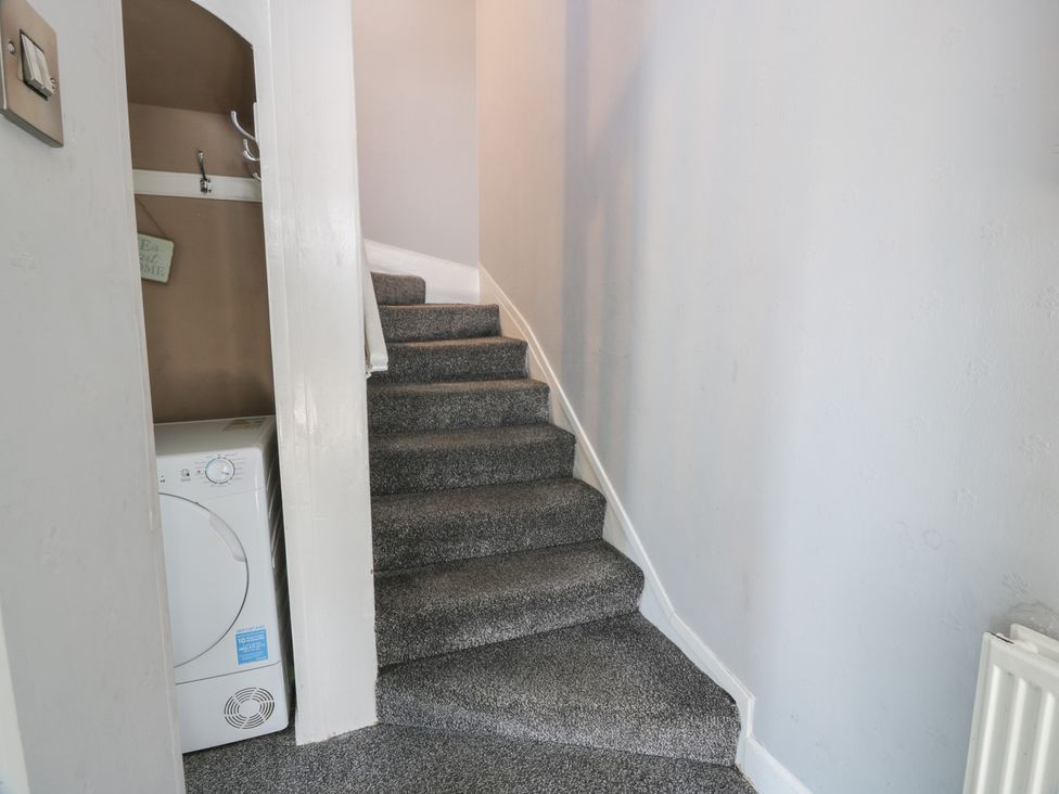A staircase with a washing machine in the hallway at Fleet Townhouse Castle Douglas
