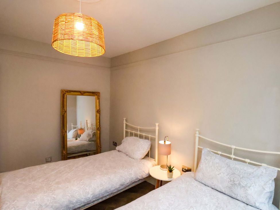 A bedroom with two beds and a mirror at 59 Moorland Road Scarborough